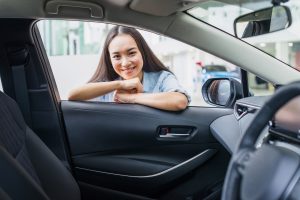 Woman smiling at her new car - Can I afford a car loan